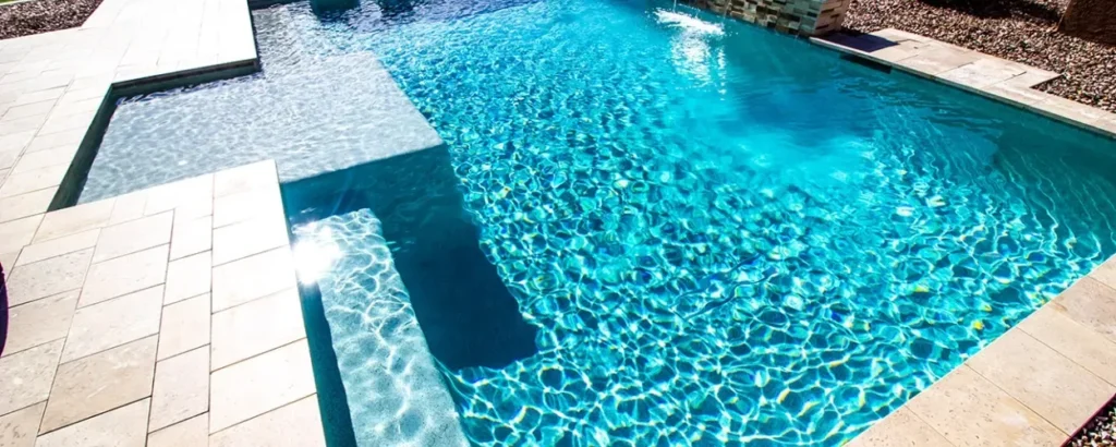 Sparkling blue swimming pool with sunlit water and tiled edges.